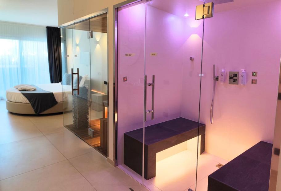 Camera moderna con sauna e doccia, letto rotondo e ampie finestre.